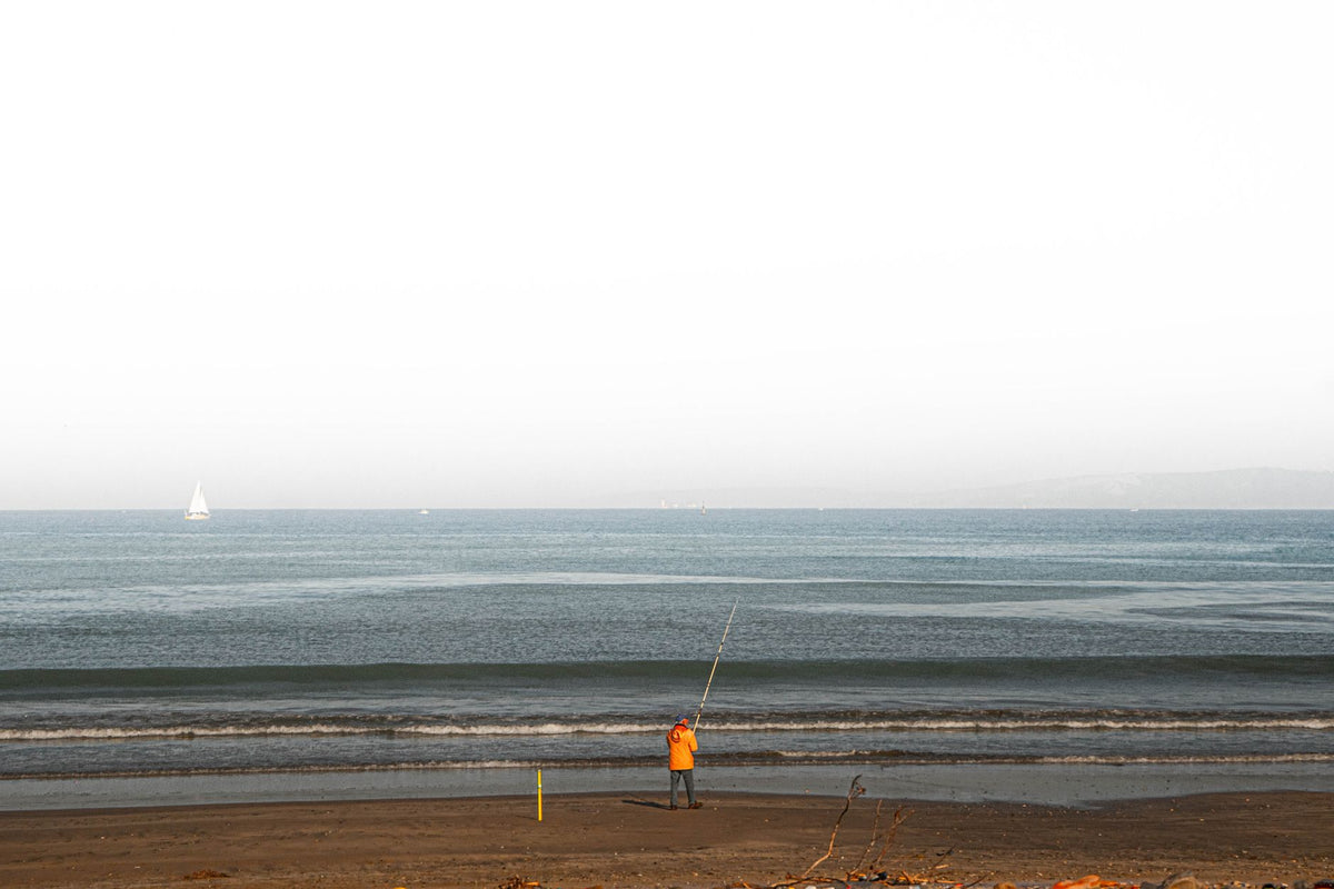 Angler launching a bait-release fishing drone from an Australian beach near a marine park boundary sign