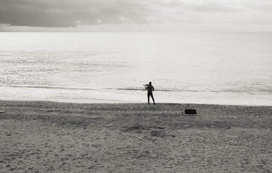 Angler launching a bait-release drone from a NSW beach with rod set up in a sand spike